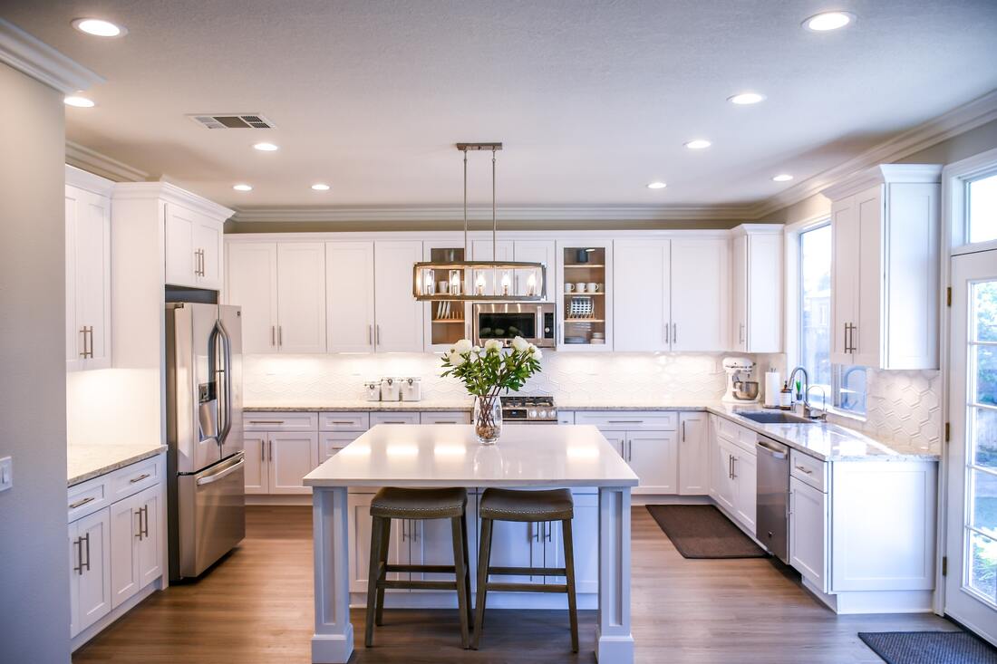 Picture of white themed kitchen in Walnut Creek house with recessed lighting and giant island in center